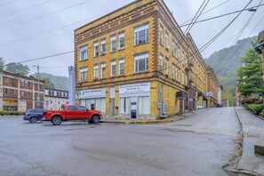 A yellow brick building with a red pickup truck parked in front. - Sunny Welch Apt: Walk to Riverfront Park! (Welch)