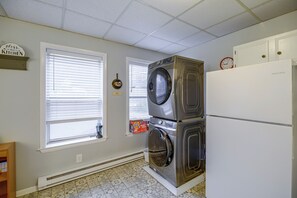 A laundry room with stacked washers and dryers, a clock, and a sign above the door. - Sunny Welch Apt: Walk to Riverfront Park! (Welch)