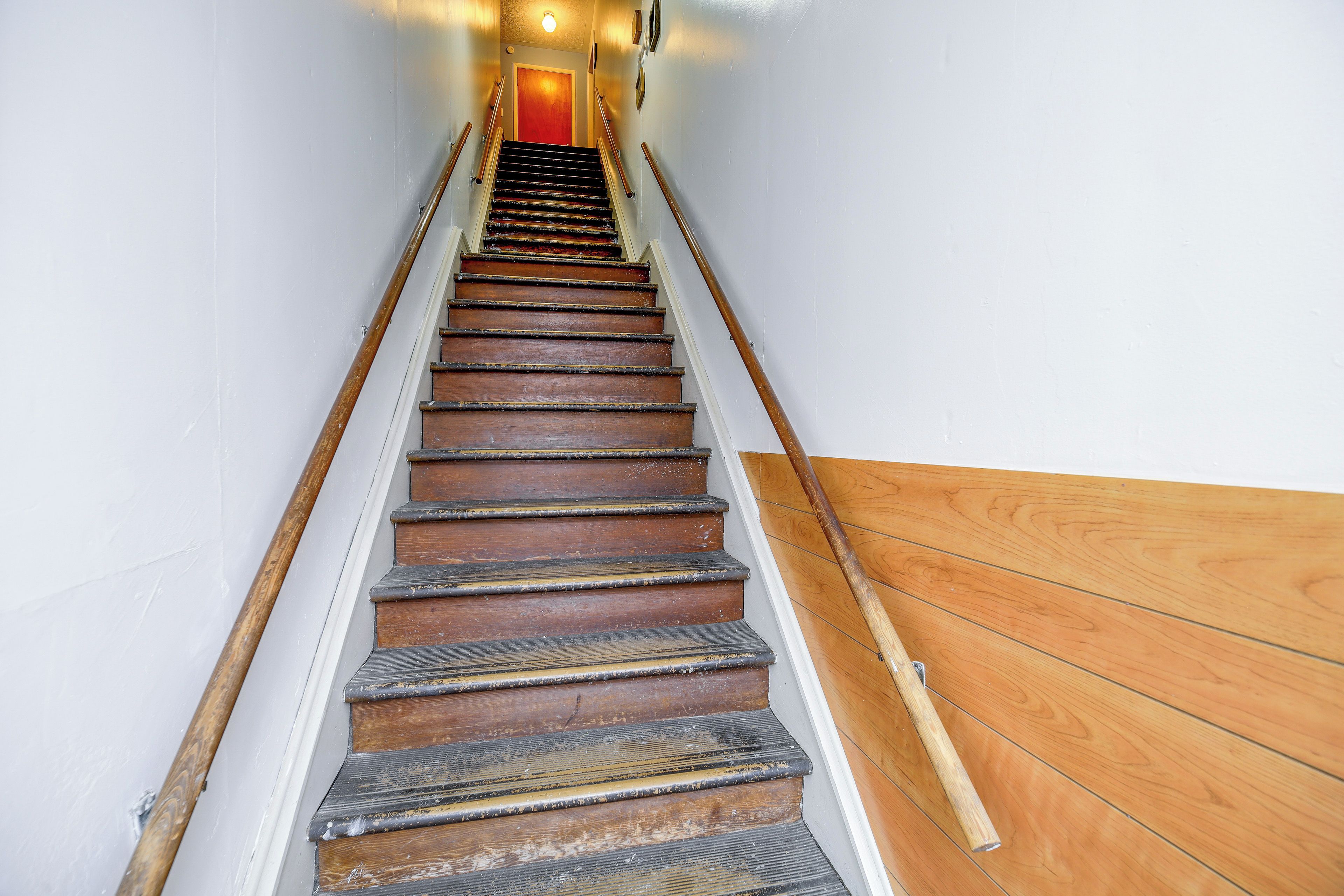 A staircase with wooden steps and metal handrails, leading to a door at the top.