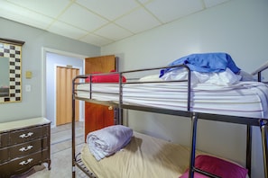 A bunk bed with a wooden headboard, a dresser with drawers, and a checkered mirror on the wall. - Sunny Welch Apt: Walk to Riverfront Park! (Welch)