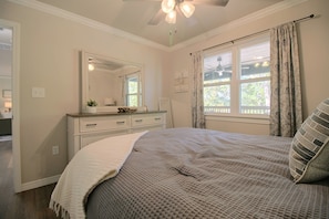 A bedroom with a bed, a dresser, a mirror, a window with curtains, and a ceiling fan. - Eucha Home: Grand Lake Views, Boat Ramp Access (Eucha)