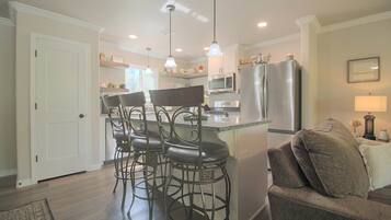 A modern kitchen with a bar area, stainless steel appliances, and a seating arrangement.