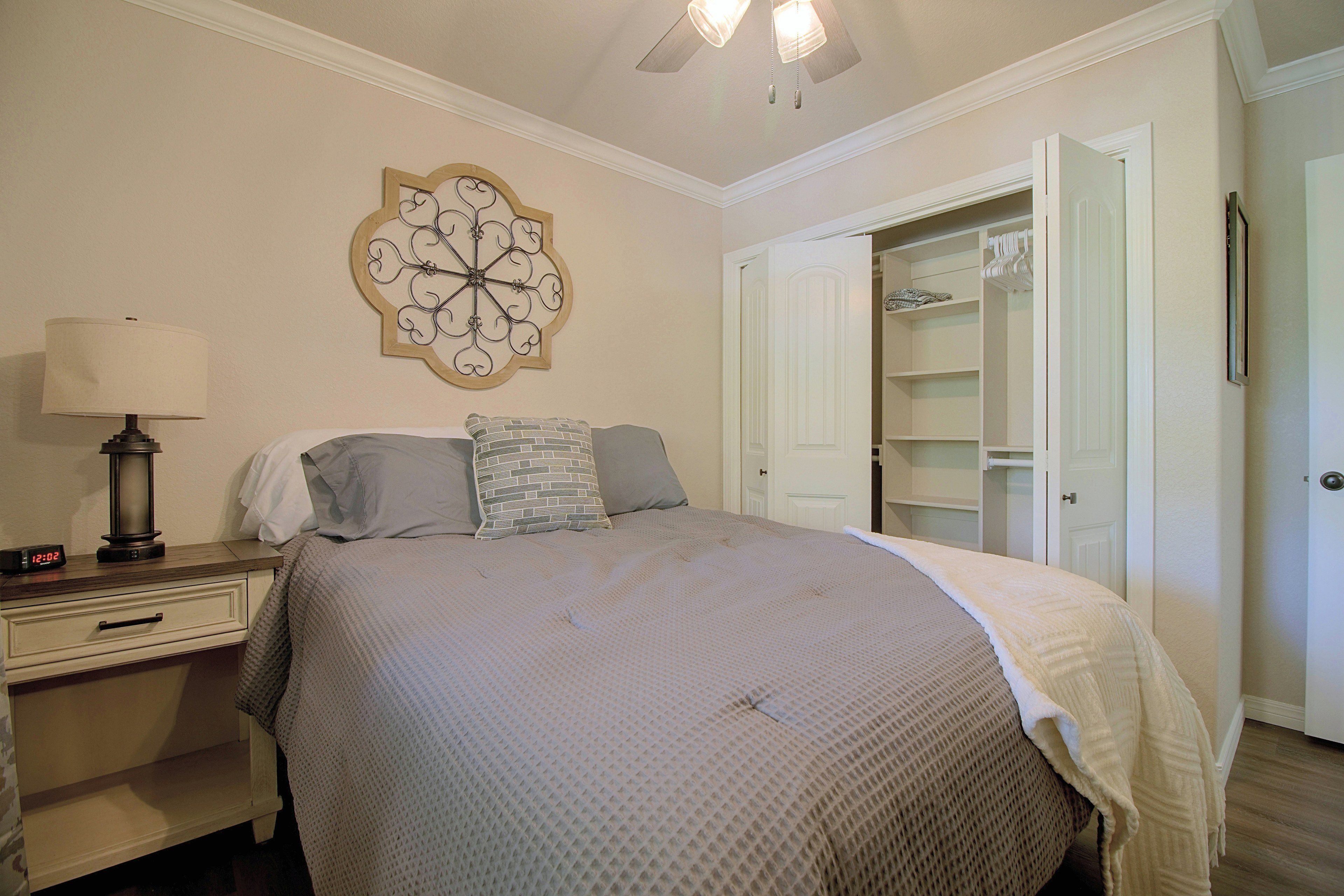 A bedroom with a bed, bedside table, lamp, and a decorative wall piece.