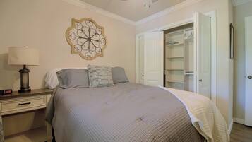 A bedroom with a bed, bedside table, lamp, and a decorative wall piece.