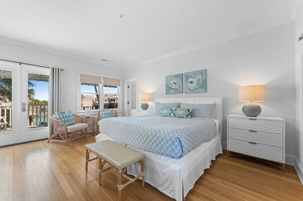 A bedroom with a large bed, a bench, a chair, a nightstand, and a view of the outdoors. - Welcome to Marsh Harbour Inn-Harbour View, a charming one-bedroom sanctuary nest (Bald Head Island)