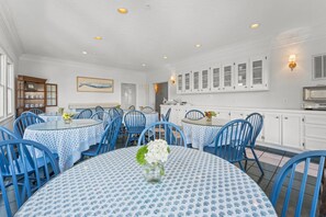 A dining area with round tables and blue chairs, white cabinets, and a kitchen area with white cabinets and a vintage radio. - Welcome to Marsh Harbour Inn-Harbour View, a charming one-bedroom sanctuary nest (Bald Head Island)