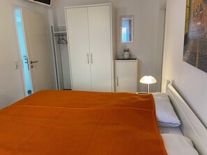 A bedroom with a bed, a wardrobe, a mirror, and a lamp. - South Beach Room (Wyk auf Foehr)