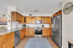 Eine moderne Küche mit Holzausstattung, Edelstahlgeräten, einem Backofen und einem großen Kühlschrank.