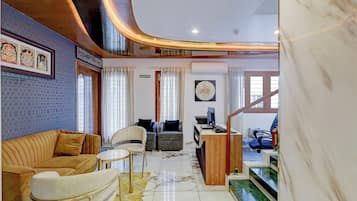 A hotel lobby with a reception desk, seating area, and a staircase leading to an upper level.