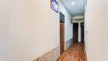 A hallway with a wooden floor, white walls, and a door with a number sign.