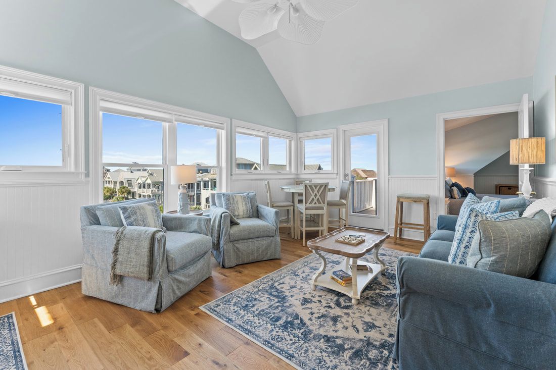 A spacious living room with a high ceiling, large windows, and a view of the city.