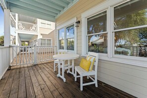 A covered porch with a white railing, a round table, and two white chairs with yellow cushions. - This enchanting handicap accessible 1st floor suite is a perfect gateway to enjo (Bald Head Island)