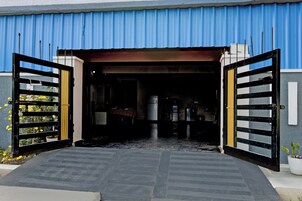 A building entrance with a blue corrugated metal roof, a black and yellow gate, and a paved pathway leading inside.