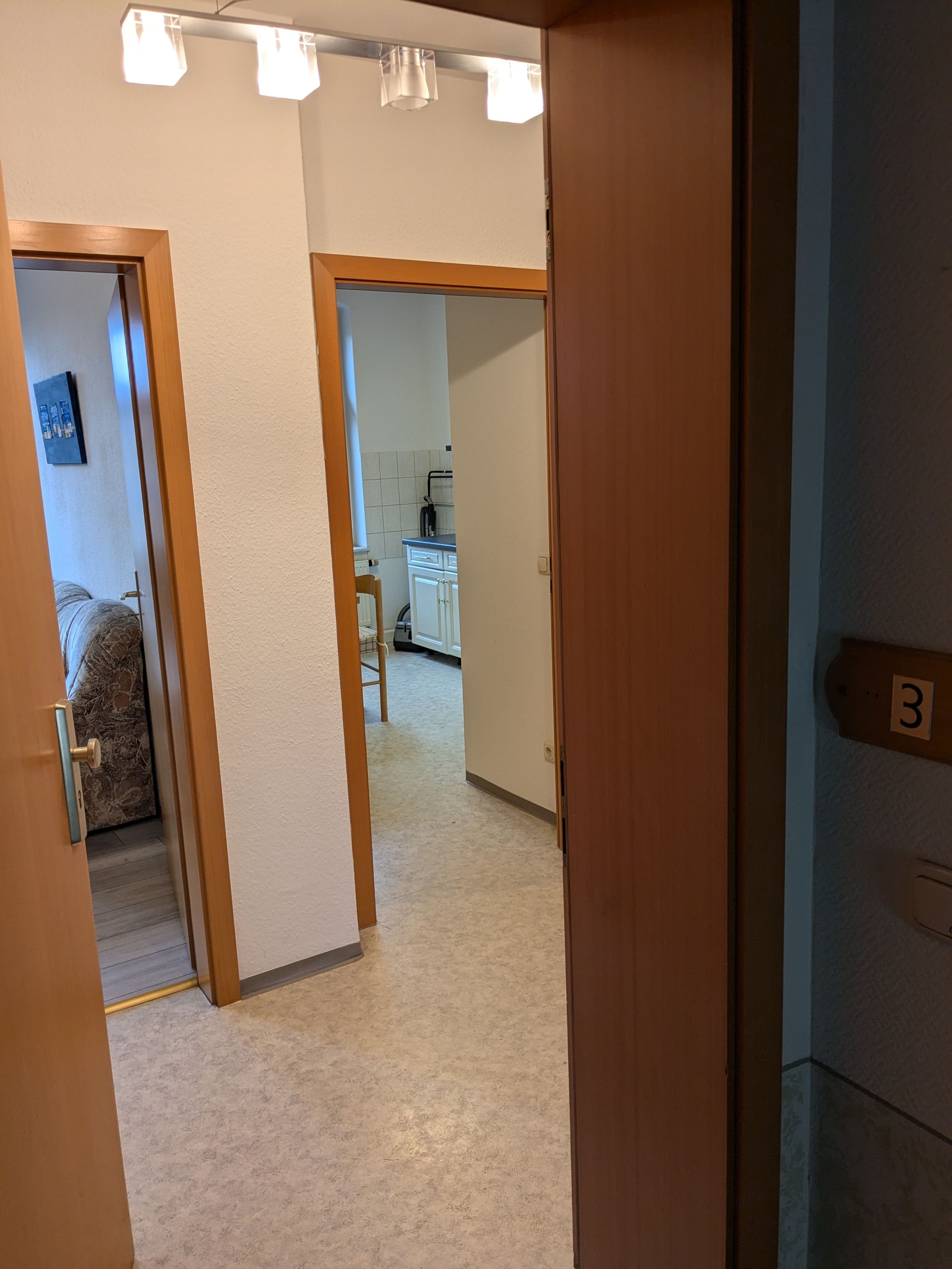 Een gang die leidt naar een slaapkamer met een bed en een badkamer.