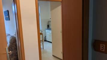 Een gang die leidt naar een slaapkamer met een bed en een badkamer.