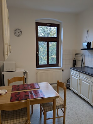 A kitchen with a window, a clock, a toaster, and a table with chairs. - Apartment 'Zuhause auf Zeit' with Garden (Gera)