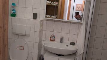 A compact bathroom with a toilet, sink, and shower.