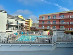 A multi-story hotel with a pool area, outdoor seating, and balconies. - 2 bedroom/bath condo in Midtown--1.5 blocks from OCMD beach (Ocean City)