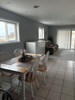 A dining area with a wooden table, white chairs, and a white cabinet. - 2 bedroom/bath condo in Midtown--1.5 blocks from OCMD beach (Ocean City)