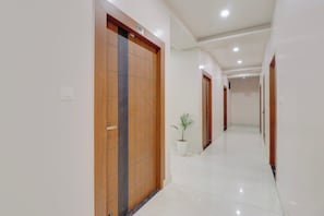 Un pasillo con puertas de madera, una planta en maceta y piso de baldosas.