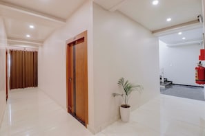A hallway with a wooden door, a potted plant, and a fire extinguisher. - Townhouse Laksar Road Haridwar (Haridwar)