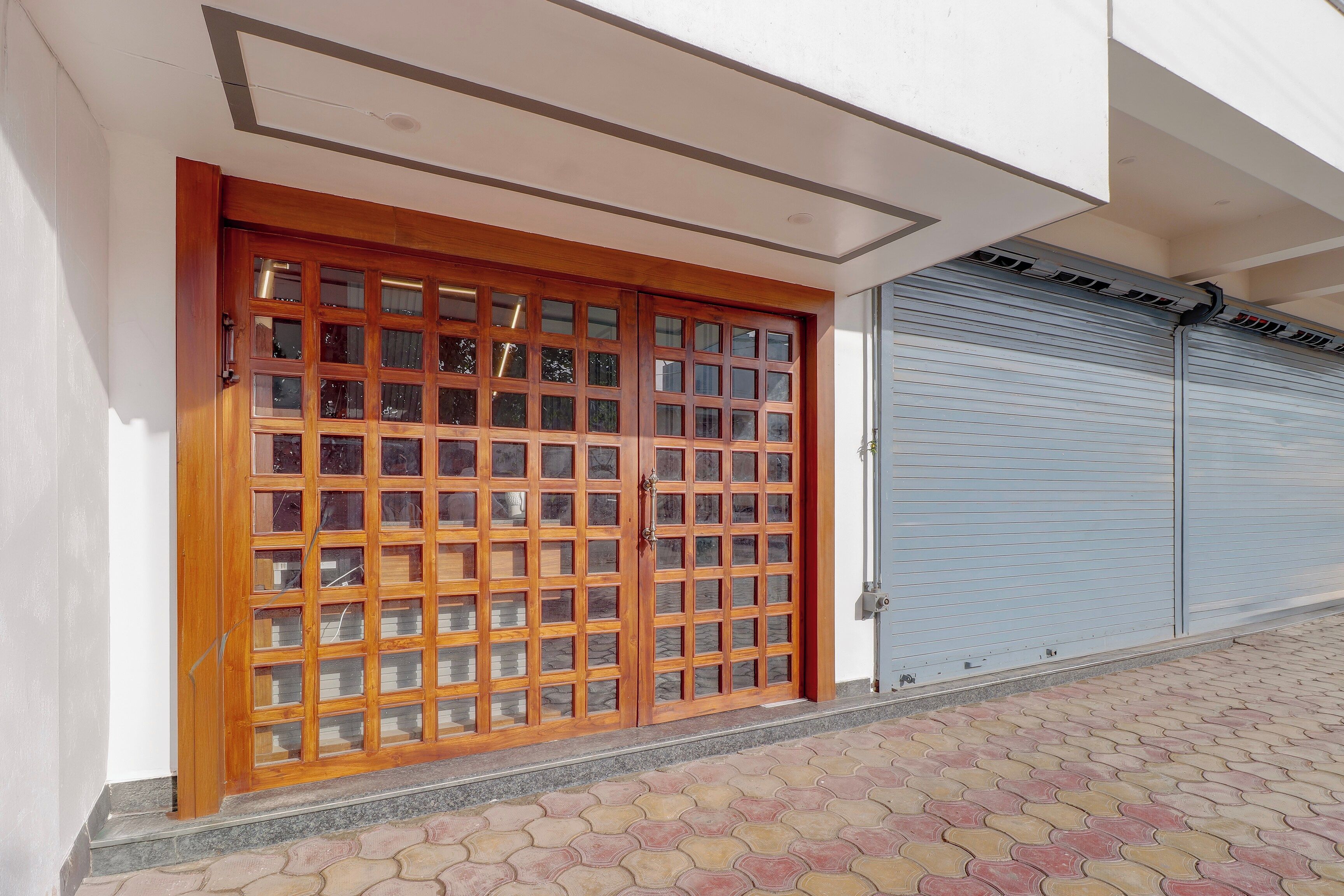 Entrada de un edificio con una puerta de madera y un persiano metálico cerrado.