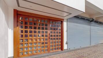 Entrada de un edificio con una puerta de madera y un persiano metálico cerrado.