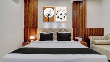 Ein Hotelzimmer mit einem Bett, zwei Nachttischen, einer Lampe, einem Sessel und zwei Wandbildern.