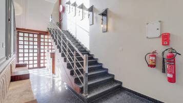 Un escalier avec des rampes en métal, un détecteur d’incendie et un extincteur fixés au mur.