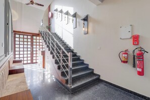 A staircase with metal railings, a fire alarm, and a fire extinguisher on the wall. - Townhouse Laksar Road Haridwar (Haridwar)
