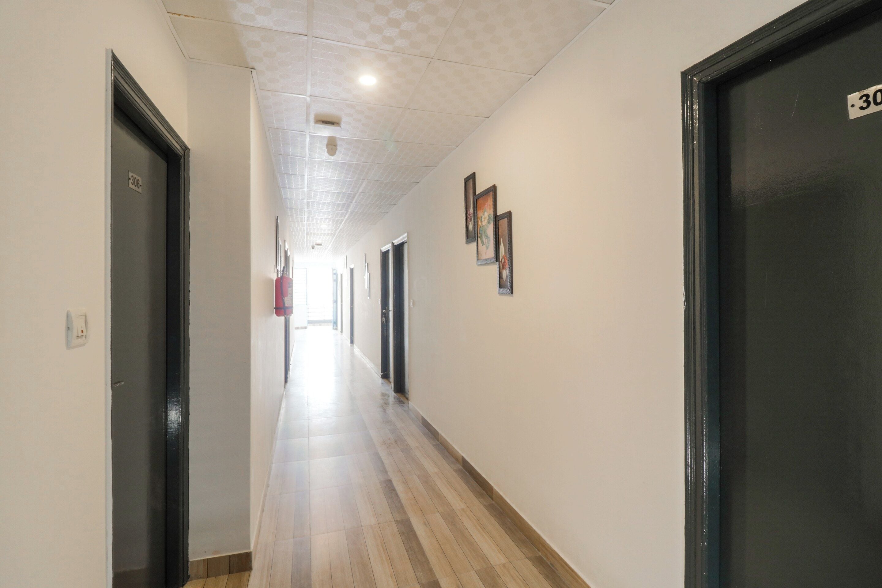 A hallway with doors on both sides, a fire alarm on the left, and a fire extinguisher on the right.