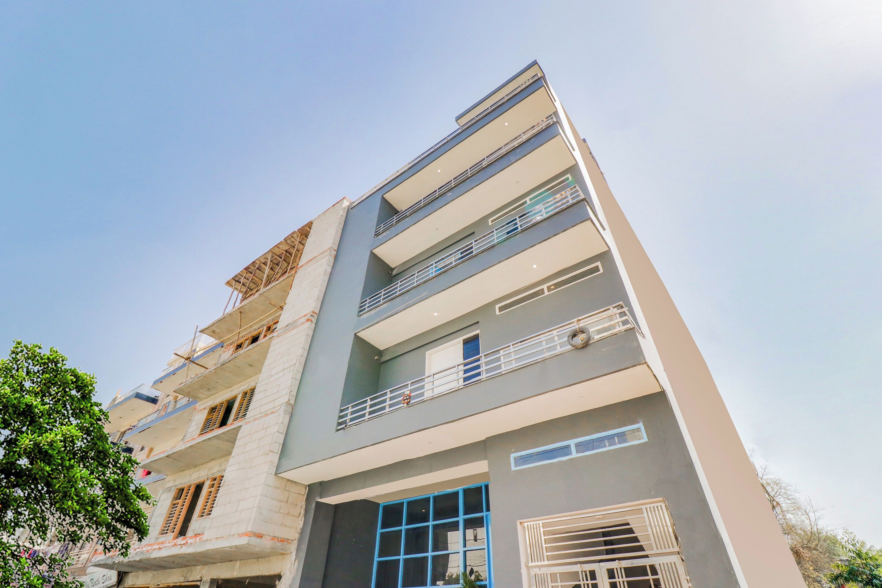 A multi-story building with balconies and a window with a blue frame.