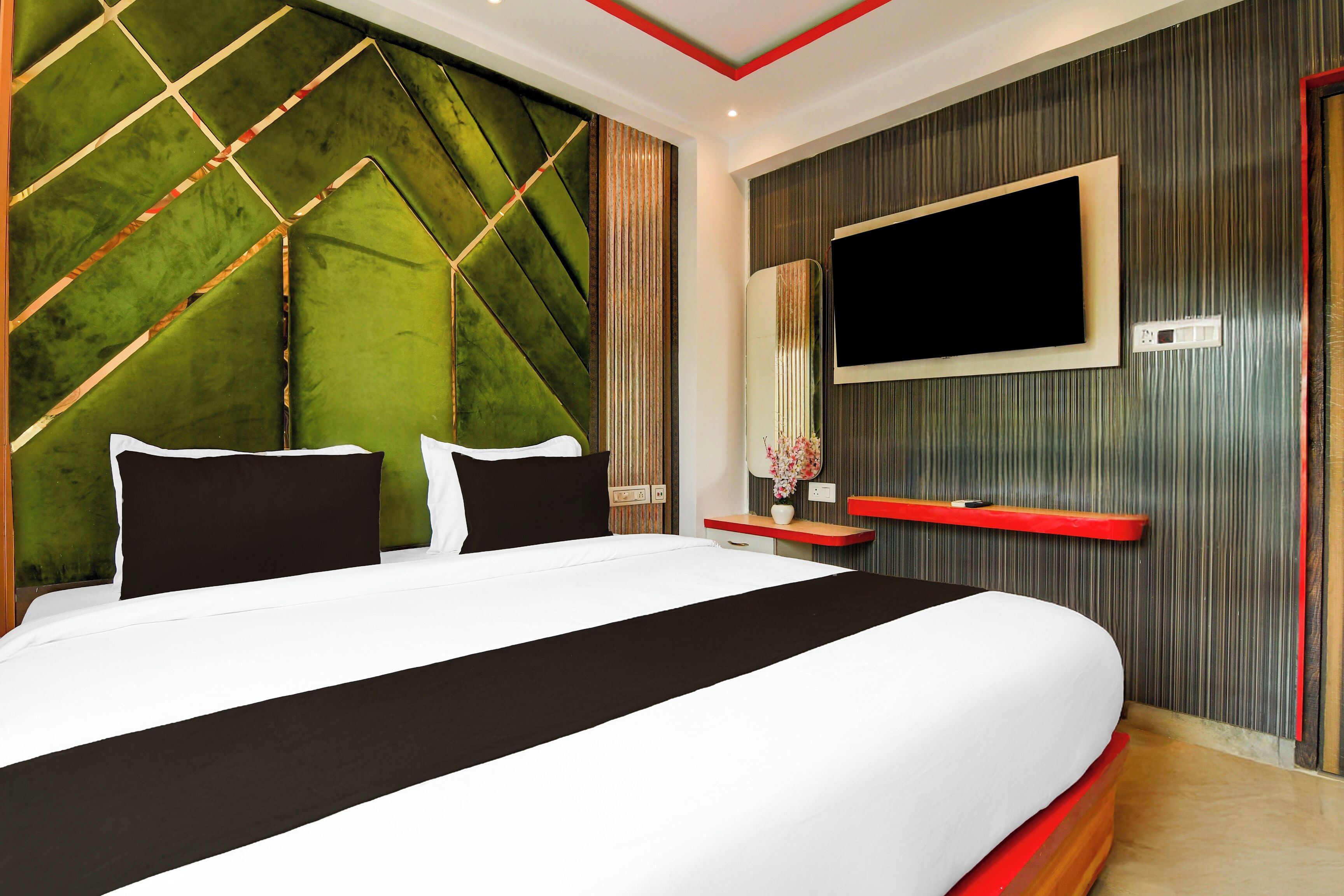 Een moderne slaapkamer met een groot bed, een aan de muur bevestigde televisie en een decoratief wandpaneel.