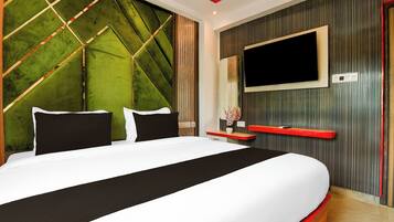 Een moderne slaapkamer met een groot bed, een aan de muur bevestigde televisie en een decoratief wandpaneel.