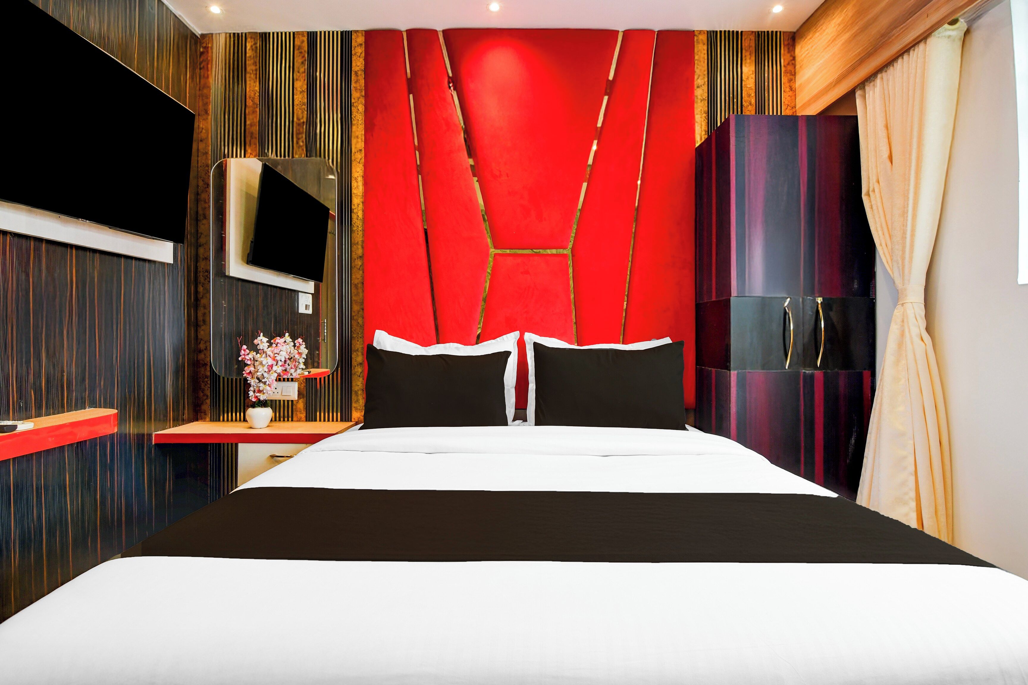 Une chambre d’hôtel moderne équipée d’un grand lit, d’une télévision, d’une armoire et d’un miroir.