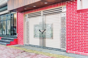 A red brick building with a large metal gate, a window with a geometric pattern, and a door with a similar design.
