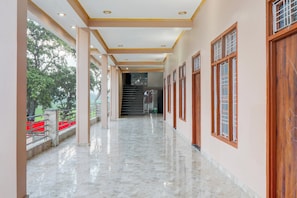 A corridor with a marble floor, wooden doors, and a staircase leading to an upper level.