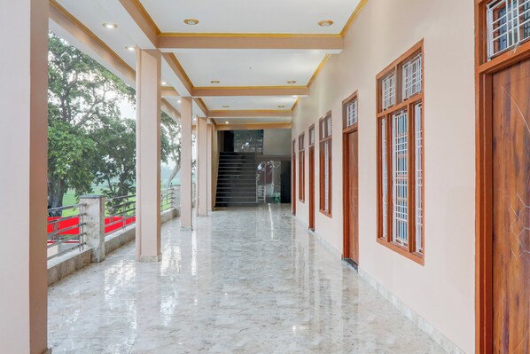 A corridor with a marble floor, wooden doors, and a staircase leading to an upper level. - Hotel O Kashvi Hotel (Misrikh)