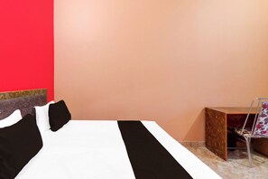 A hotel room with a bed, a small side table, and a chair.