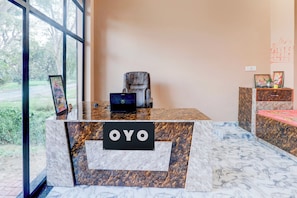 A reception desk with a marble top, a framed picture, and a sign that reads 'OYO'.