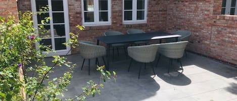 Un patio con una mesa y sillas, un muro de ladrillo y una ventana.