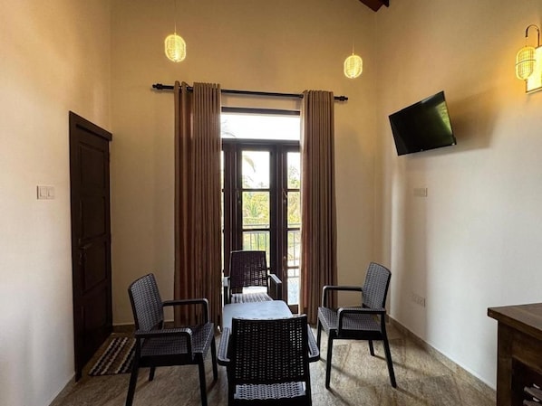 Une pièce comprenant une table à manger, quatre chaises, un téléviseur à écran plat fixé au mur et une porte.