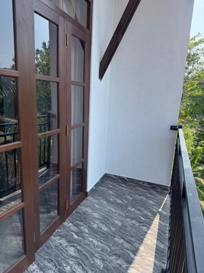 Un balcon avec une porte en bois donnant sur un paysage verdoyant.