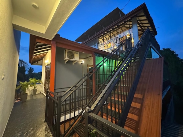 A multi-level building with a staircase, outdoor seating area, and potted plants.