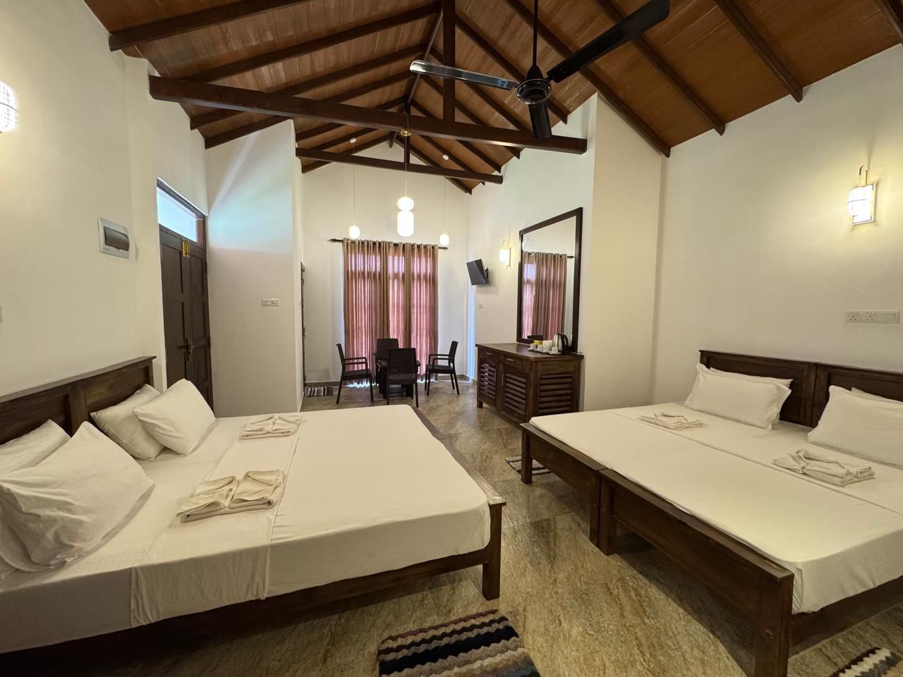 Habitación de hotel con dos camas, un escritorio, una silla y un espejo.