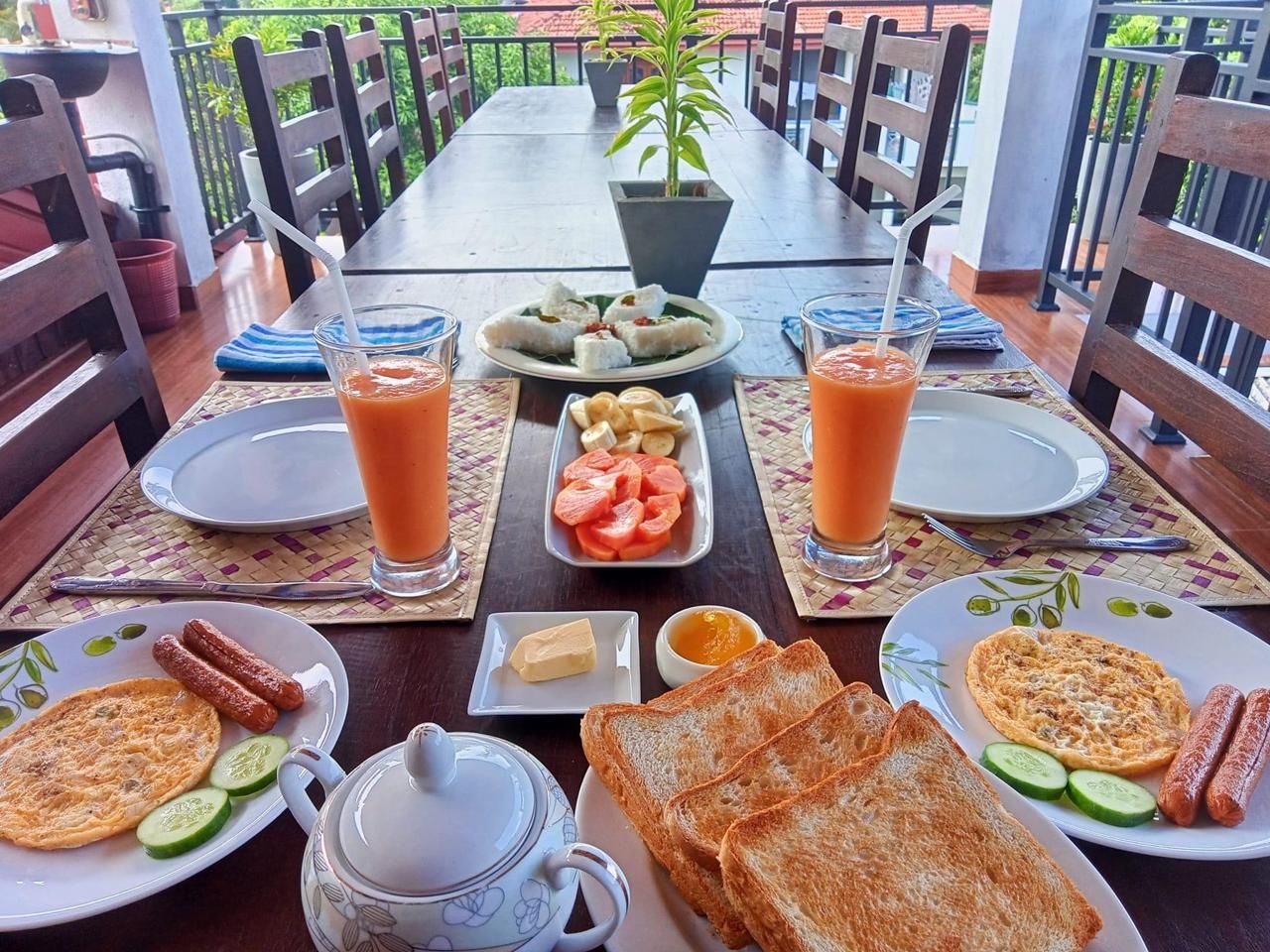 Una escena de desayuno con platos de comida, bebidas y una jarrón.