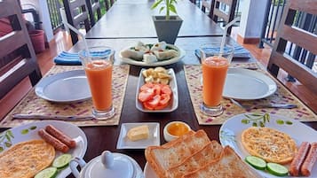 Una escena de desayuno con platos de comida, bebidas y una jarrón.