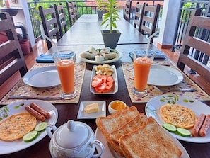 A breakfast setting with plates of food, drinks, and a pitcher.