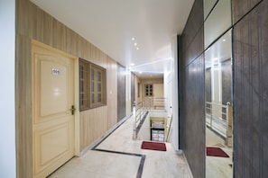 A hallway with doors numbered 101 and 103, a staircase, and a red carpet. - Hotel O Galaxy (Faridabad)