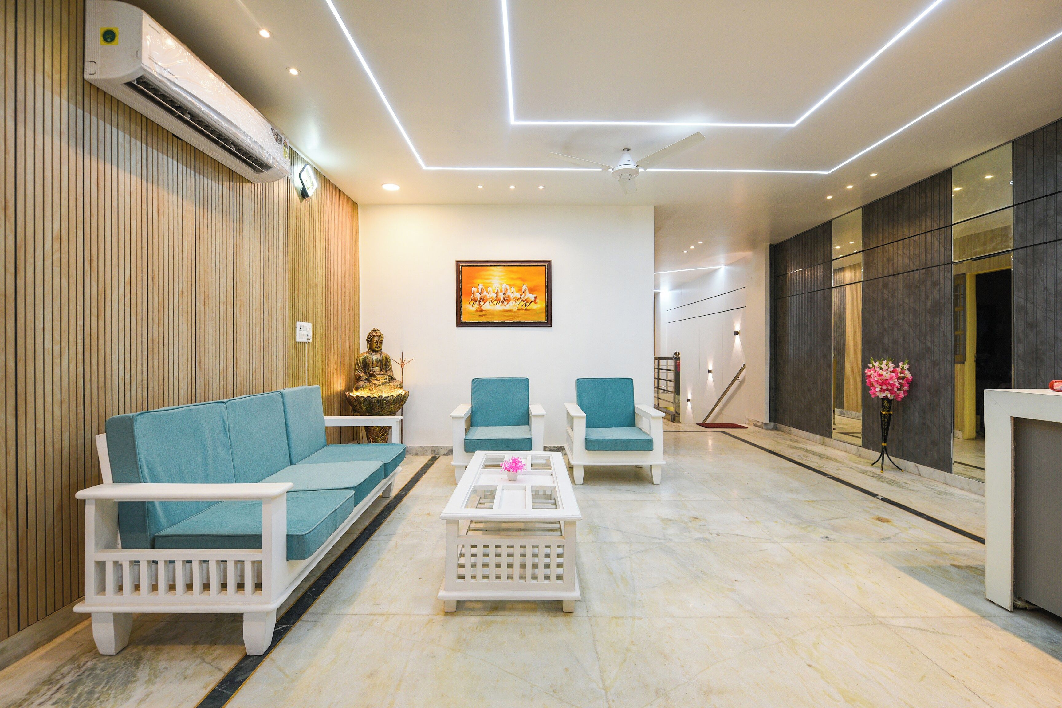 Una sala de estar moderna con un sofá, dos sillones, una mesa de centro y una estatua de Buda.